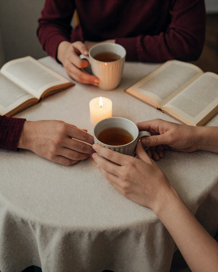 Two hands gently touching over a cafe table by candlelight - cover image for small penis sex intimacy category